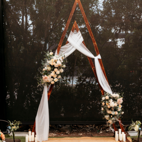Rustic timber arch with floral, white sash and candles